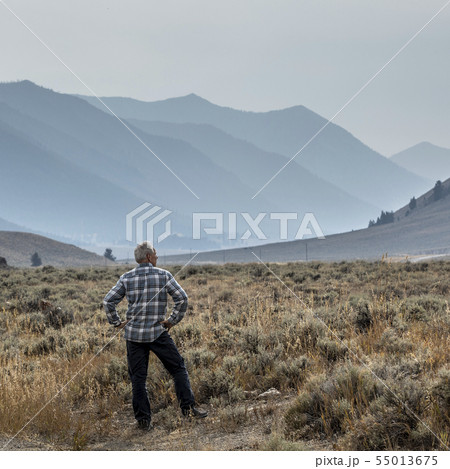 Senior man standing in field by mountains in Sun Valley, Idaho, USA Senior man standing in field by mountains in Sun Valley, Idaho, USA 55013675