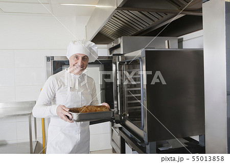 Chef holding meat in roasting tray by oven 55013858