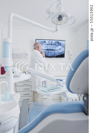 Dentist examining X-ray on television screen Dentist examining X-ray on television screen 55013902