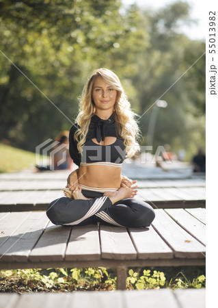 Young woman practicing yoga on boardwalk 55013982