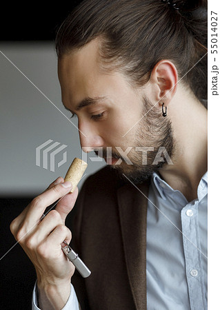 Young man smelling wine on cork at tasting Young man smelling wine on cork at tasting 55014027