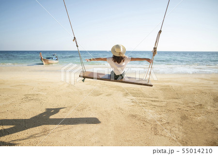 Young woman on swing at beach 55014210