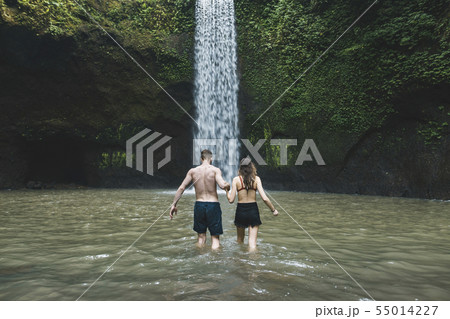 Young couple holding hands in river by Tibumana Waterfall in Bali, Indonesia 55014227