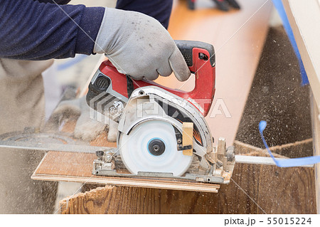 床材を電動丸ノコでカットしている職人の手元クローズアップの写真素材