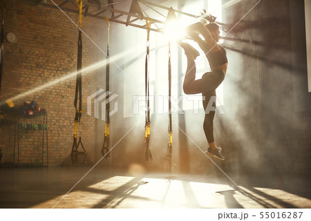 Perfect flexibility. Full length of athletic woman in black sport clothing jumping while exercising Perfect flexibility. Full length of athletic woman in black sport clothing jumping while exercising 55016287