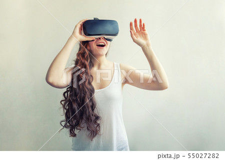 Smile young woman wearing using virtual reality VR glasses helmet headset on white background Smile young woman wearing using virtual reality VR glasses helmet headset on white background 55027282