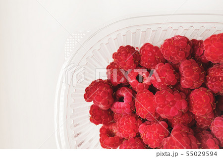 Close-up ripe juicy and delicious raspberry in a plastic transparent dish on a light background 55029594