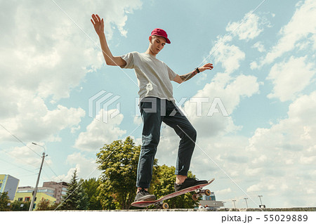 Skateboarder doing a trick at the city's street in sunny day 55029889