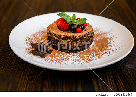 Chocolate fondant (lava cake) decorated with strawberries and cocoa powder Chocolate fondant (lava cake) decorated with strawberries and cocoa powder 55039564