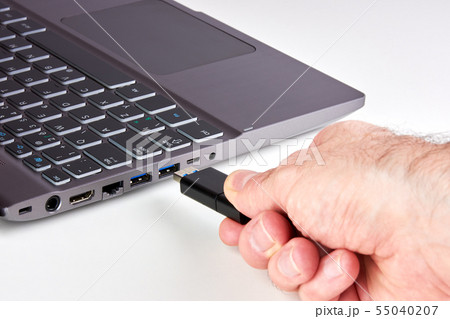 Hand of a man plugging a black USB Flash drive 55040207