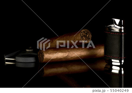 Cigar with cutter and lighter, reflected on a 55040249
