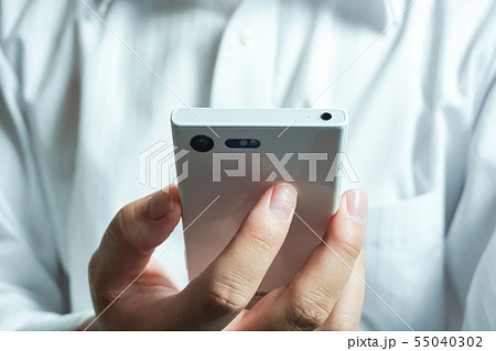 スマートフォンを見ている人 ワイシャツを着た人物の背景 スマートフォンを見ている人 ワイシャツを着た人物の背景 55040302