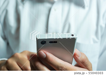 スマートフォンを見ている人　ワイシャツを着た人物の背景 55040303