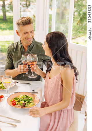 Dark-haired wife wearing pink dress drinking wine with husband 55043833