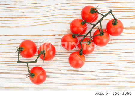 Ripe cherry tomatoes on a twig on a white woden 55043960