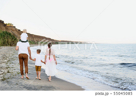 Family of four walking along the seashore. Parents 55045085