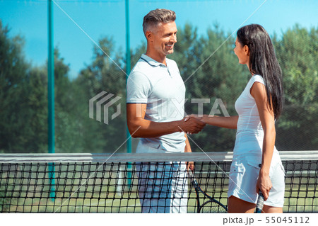 Handsome man smiling after playing tennis with beautiful wife Handsome man smiling after playing tennis with beautiful wife 55045112