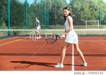 Woman wearing white sneakers playing tennis with husband 55045152