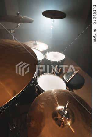 Modern drum set prepared for playing in a dark rehearsal room on stage with a bright spotlight. The 55046141