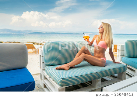 Woman holding Delicious classic iced aperol spritz cocktail with ice cubes on a hot tropical beach Woman holding Delicious classic iced aperol spritz cocktail with ice cubes on a hot tropical beach 55048413