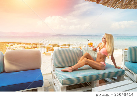 Woman holding Delicious classic iced aperol spritz cocktail with ice cubes on a hot tropical beach 55048414