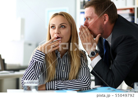 Male clerk sharing some secret knowledge with female colleague 55049792