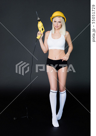 Sexy woman with a drill. Woman builder in construction helmet. Sexy woman with a drill. Woman builder in construction helmet. 55051729