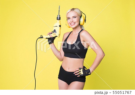 Young sexy woman in headphones holding a drill. Woman builder. Young sexy woman in headphones holding a drill. Woman builder. 55051767