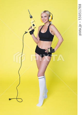Young sexy woman in headphones holding a drill. Woman builder. 55051768