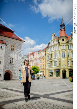 woman in sunglasses and backpack in aged city center square. Poland 55053757