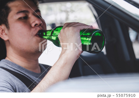 Young asian man drives a car with drunk a bottle Young asian man drives a car with drunk a bottle 55075910