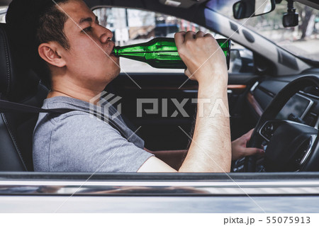 Young asian man drives a car with drunk a bottle 55075913