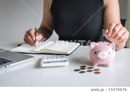Woman putting golden coin in pink piggy bank for Woman putting golden coin in pink piggy bank for 55076676