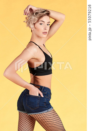 girl with raised arm in short jeans standing with a hand in his pocket 55079216