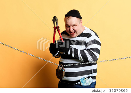 burglar with scissors in hands looking at the camera while standing behind the chain 55079366