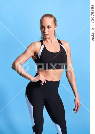 beautiful Caucasian female bodybuilder with hands on hips standing at gym. 55079898