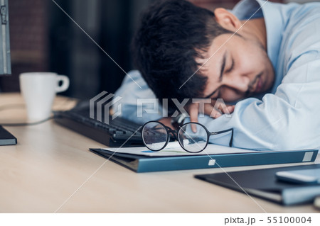 Tired asian businessman sleep on working desk 55100004