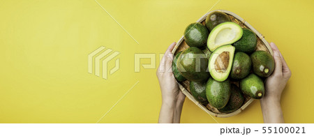 Hand holding organic avocados half cut with seed Hand holding organic avocados half cut with seed 55100021