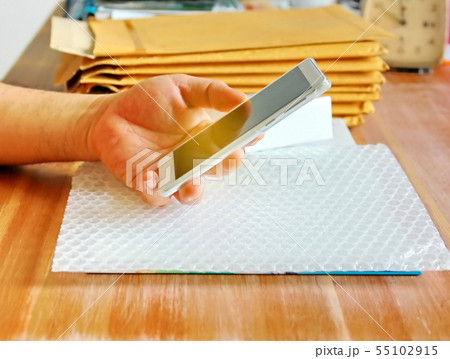 hand using smartphone in parcel delivery shop.  55102915