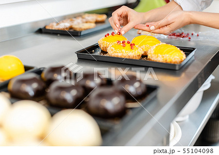 Pastry chef putting cranberries on top of little tartelettes Pastry chef putting cranberries on top of little tartelettes 55104098