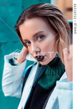 Blue-eyed fashion model with dark lipstick posing outside Blue-eyed fashion model with dark lipstick posing outside 55107259