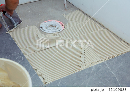 Hands of the tiler are laying the ceramic tile on Hands of the tiler are laying the ceramic tile on 55109083