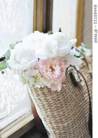 Feminine wedding still life composition. Straw French basket bag with pink peonies flowers and Feminine wedding still life composition. Straw French basket bag with pink peonies flowers and 55109449
