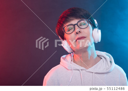 Hobby and leisure concept - Middle-aged woman listening music on blue background. 55112486