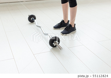 Unidentified young girl with barbell in the spacious bright gym to perform exercises. Concept of 55112824
