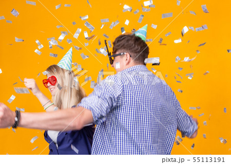 Fun, holidays and party concept - Couple dancing among falling confetti on yellow background 55113191