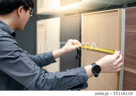 Asian man using tape measure on cabinet materials 55116119