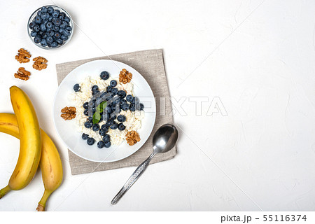 Healthy breakfast. Cottage cheese with blueberry, nuts, honey and mint in a white bowl on a white Healthy breakfast. Cottage cheese with blueberry, nuts, honey and mint in a white bowl on a white 55116374