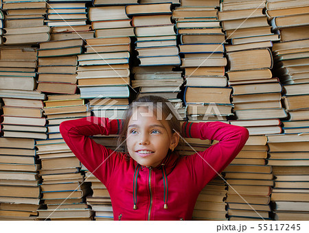 Close up portrait of a dreaming smiling schoolgirl over bookshelf background Close up portrait of a dreaming smiling schoolgirl over bookshelf background 55117245