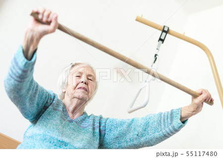 Elderly 96 years old woman exercising with a stick sitting on her bad. Elderly 96 years old woman exercising with a stick sitting on her bad. 55117480